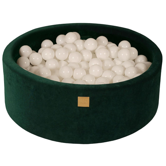 A round dark green velvet ball pit with a zipper, filled with white balls and a dark green carpet-like bottom.