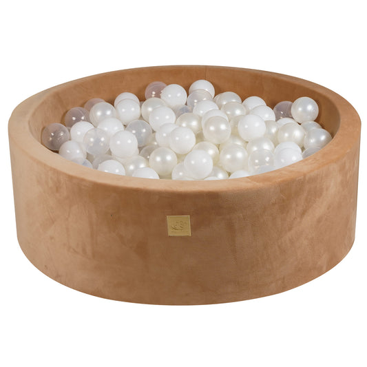 A round beige velvet ball pit filled with white balls, with a zippered cover on top.