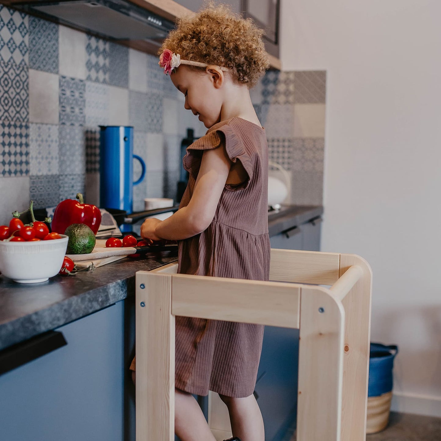 Toddler helping on a kitchen helper stool in the kitchen.