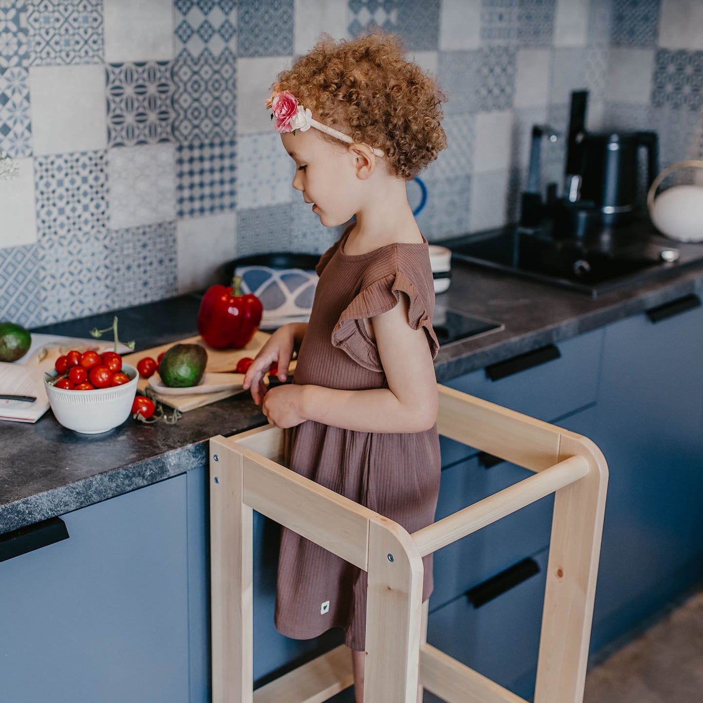 Close-up of a toddler helping on a kitchen helper stool in a kitchen.