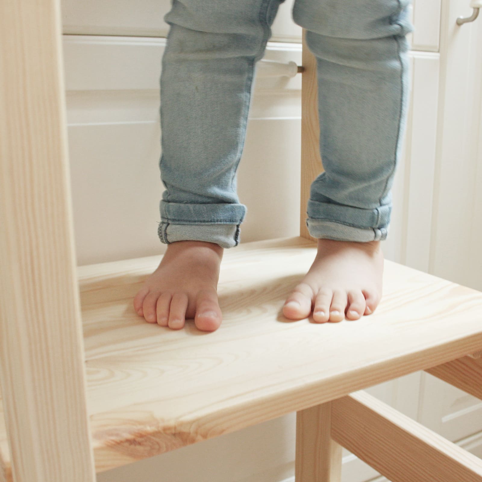 Close-up of toddler’s feet on a kitchen helper stool.
