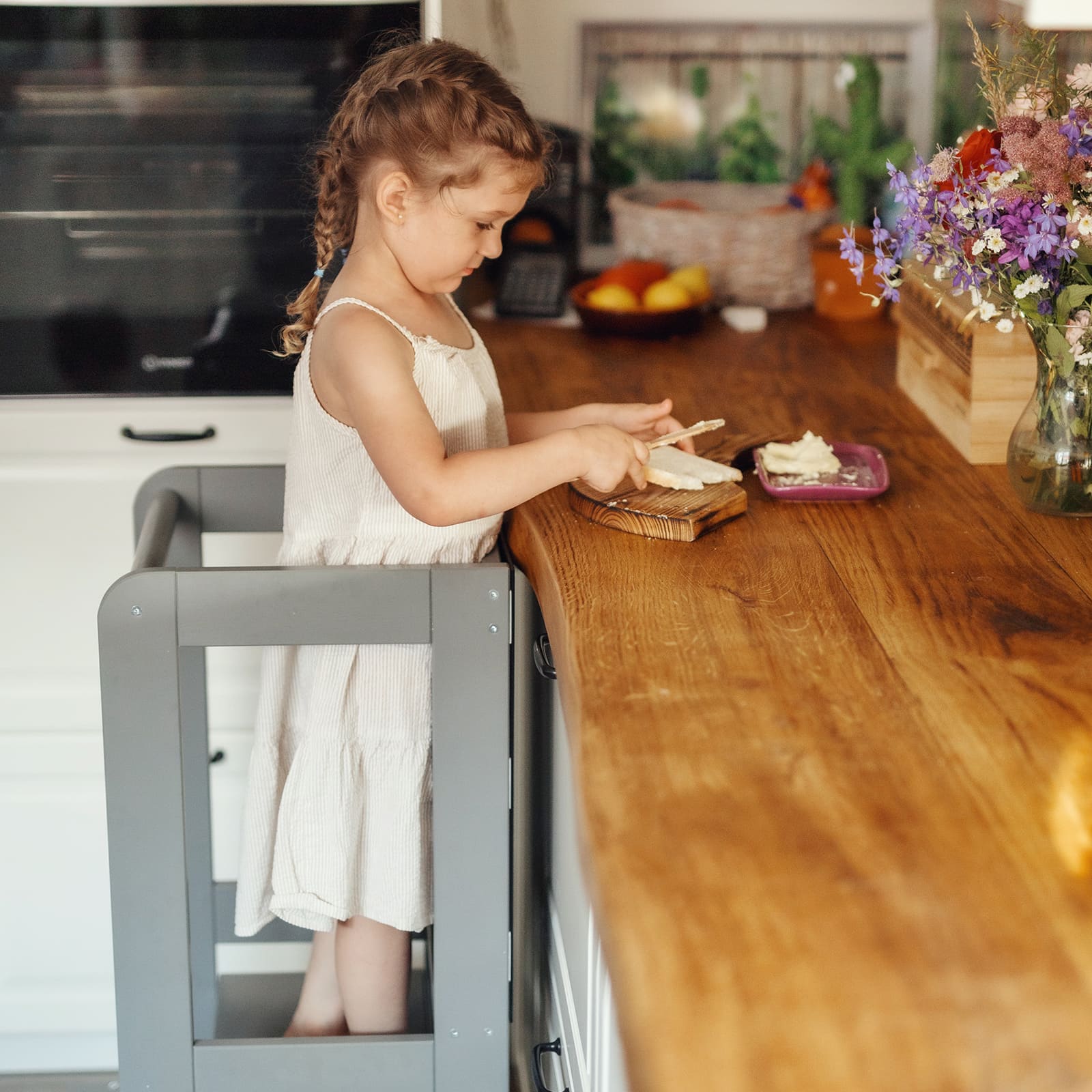 Side view of a toddler in a kitchen setting, using a kitchen helper stool.