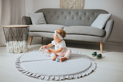 Crushed light-grey velvet play mat for babies, with a toddler playing with a toy.