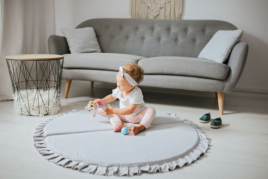 Crushed light-grey velvet play mat for babies, with a toddler playing with a toy.