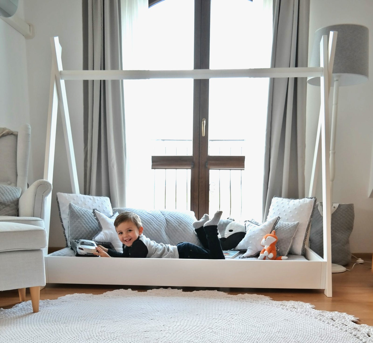 White frame play set with a toddler smiling at the camera.