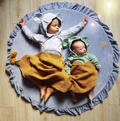 Crushed grey velvet play mat for babies, with two toddlers sleeping on a wooden floor background.